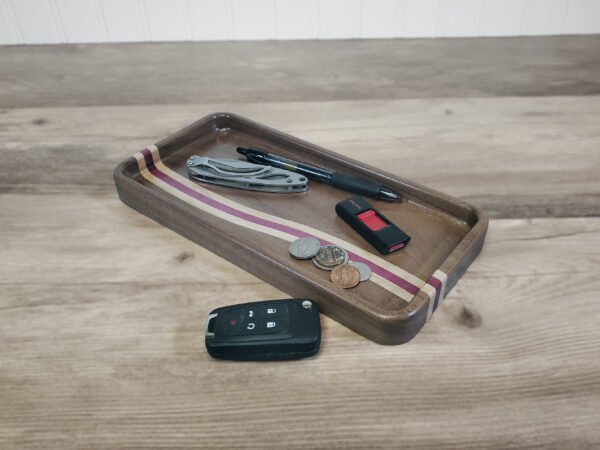 Walnut catchall tray with maple and purpleheart ocean wave stripe and everyday carry items.